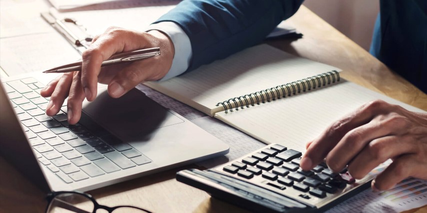 Close up of a man calculating tax returns and recording them in a insecure hard copy format.